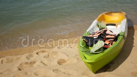 用桨划在沙滩上的皮艇被蓝色的海水冲刷波浪状的水晶水中泛着五颜六色的独木舟热带寂寞视频的预览图