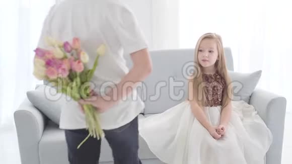 一个穿便服的高加索男孩背着一束郁金香向可爱的女孩走来惊讶视频的预览图