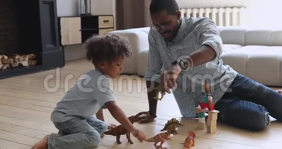 快乐的美国爸爸和小儿子在家玩恐龙视频的预览图