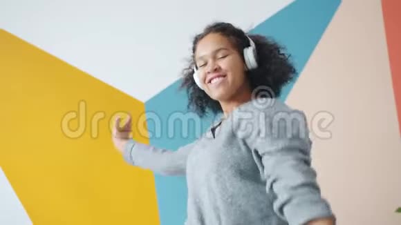 美国黑人学生戴耳机在室内跳舞的快乐画像视频的预览图