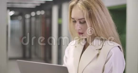 美丽的金发白种人女人站在露天办公室看着摄像机微笑着视频的预览图