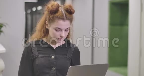 一位自信的红发白种人女人在笔记本电脑键盘上打字看着相机微笑着成功的青年视频的预览图