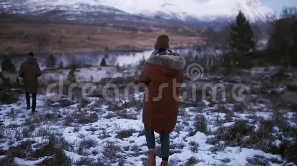 两名游客慢吞吞地穿过乡村走向背景上的雪山山峰一个人视频的预览图