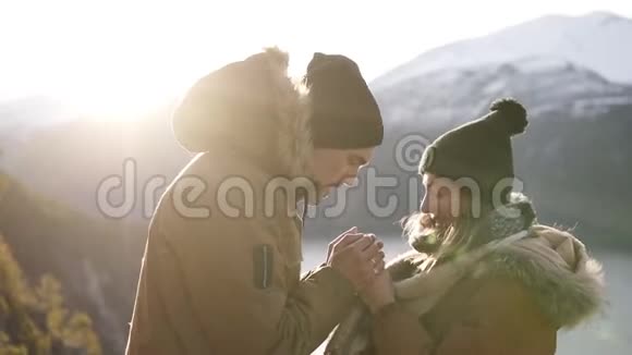 年轻的一对穿着冬衣的夫妇站在一起手牵着手走向美丽的雪山和湖泊一个男人视频的预览图