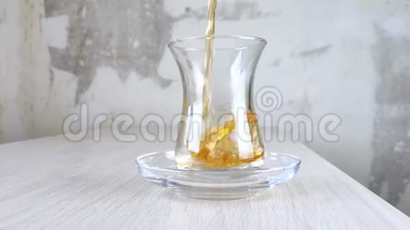 土耳其红茶倒入国杯在透明杯和木桌上的茶托中特写棕色饮料琥珀视频的预览图