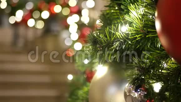 在模糊的闪闪发光的仙女背景上用鲜艳的红色球特写装饰的户外圣诞树视频的预览图