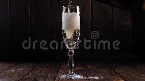 特写的香槟在木制背景上倒入一个玻璃杯中动作缓慢视频的预览图