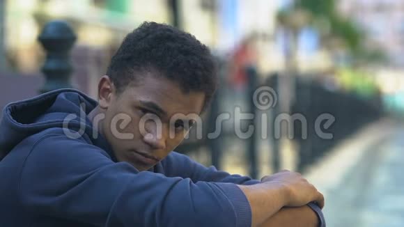 悲伤的黑人少年坐在城市街道上逃离家尴尬的年龄问题视频的预览图