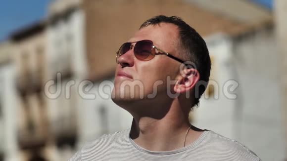 漂亮的年轻人戴着眼镜抬头看着在阳光明媚的日子里站在户外视频的预览图
