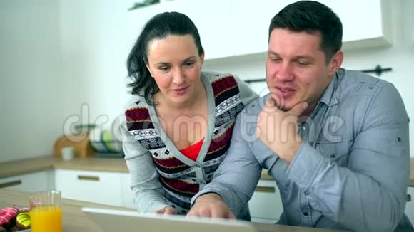 白人夫妇在厨房用电脑家庭技术和人际关系概念微笑的夫妻视频的预览图