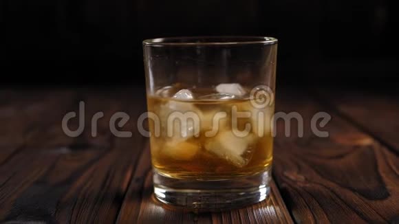 单一麦芽威士忌加冰块在木制背景上特写镜头慢动作视频的预览图
