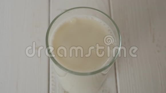在轻木质的表面上滴入满杯牛奶的奶液视频的预览图