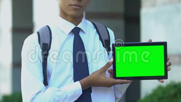 学生展示带有绿色屏幕的平板电脑为电子书图书馆应用程序做广告视频的预览图