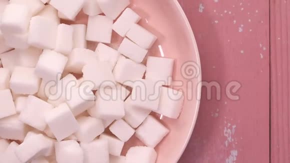 顶部的糖立方体在一个碗的粉红色背景视频的预览图