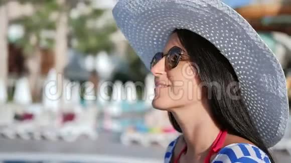 在阳光明媚的海滩上一位笑得时尚的旅游女性微笑着放松着视频的预览图