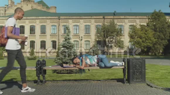 疲惫的学生在公园的长椅上坐着笔记本电脑视频的预览图