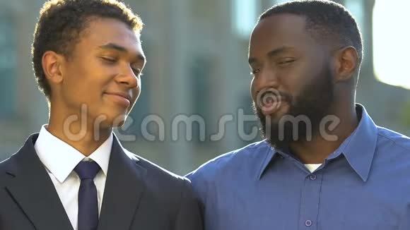 非裔美国人的父亲和儿子穿着正装看着相机微笑着家人视频的预览图