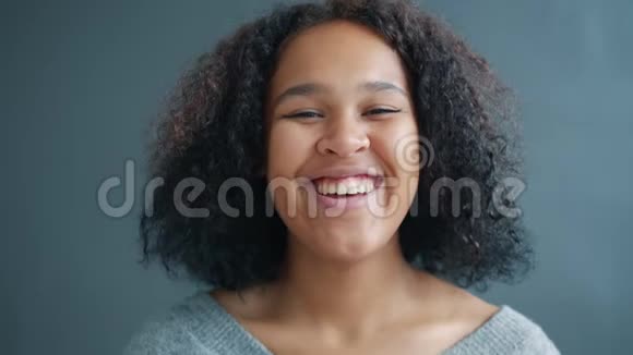 一位可爱的非洲裔美国女士站在灰色背景下大笑视频的预览图