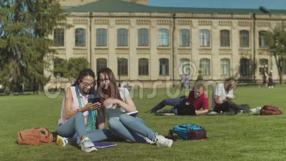 两个女大学朋友在校园草坪上闲聊视频的预览图