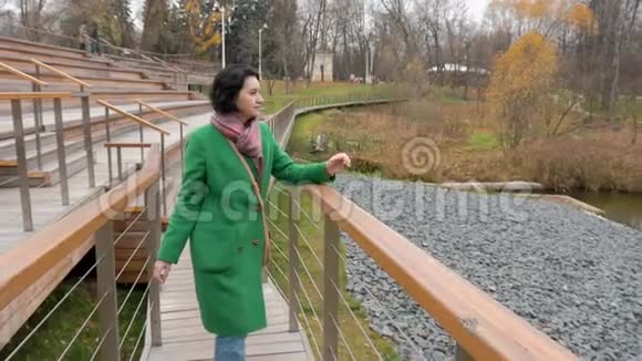 中年白种人妇女沿着公园前景的窄木地板散步视频的预览图