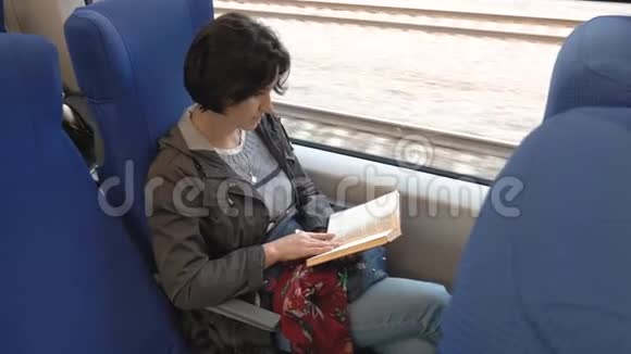 一个中等身材的女人坐在火车上读一本书视频的预览图