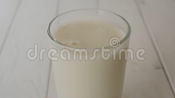 一整杯新鲜牛奶慢慢地在轻木质面上旋转视频的预览图