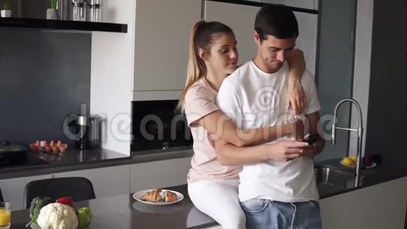 一个男人专注于他的手机而他的女朋友妻子正在试图引起他的注意从后面拥抱他一个年轻人视频的预览图