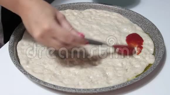 用勺子把番茄酱洒在披萨面团上视频的预览图