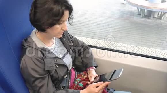 白种人女人坐在窗边看着平板电脑屏幕视频的预览图