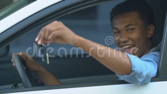 快乐的黑人男青少年在司机的地方显示汽车钥匙第一辆汽车视频的预览图