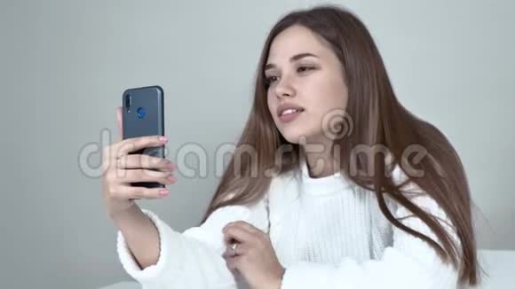 一个抱着智能手机看镜头的高加索女孩的特写镜头视频的预览图