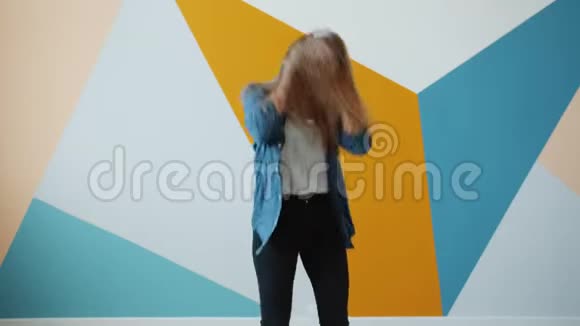 可爱的年轻女士戴着无线耳机在五颜六色的背景上跳舞视频的预览图
