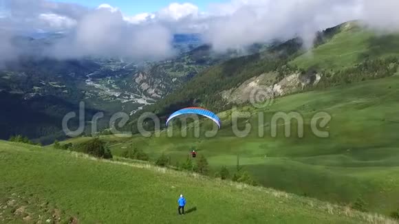 滑翔伞用降落伞飞过青山和田野视频的预览图