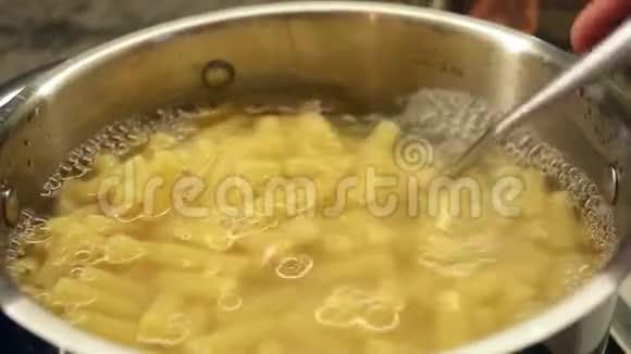 金属锅中沸水中的意大利面女性手搅动意大利面视频的预览图