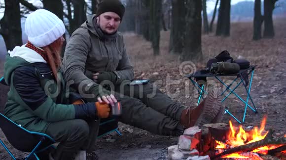 有几个人坐在炉火旁的光椅上寒冷的秋晚在森林里积极的生活方式旅行度假视频的预览图