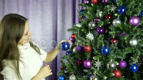 漂亮的小女孩把圣诞树打扮得很可爱视频的预览图