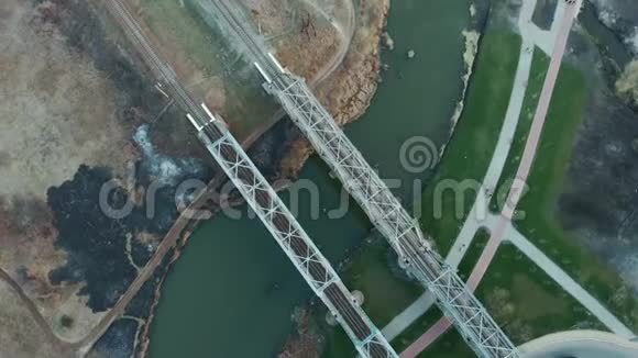 高速列车轨道在凸起的平台上跨河的现代铁路钻在金属铁路桥上旋转视频的预览图