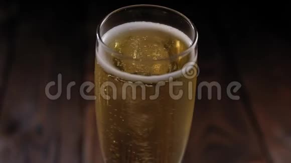 在木制表面上缓慢旋转的气泡的香槟杯的特写视频的预览图