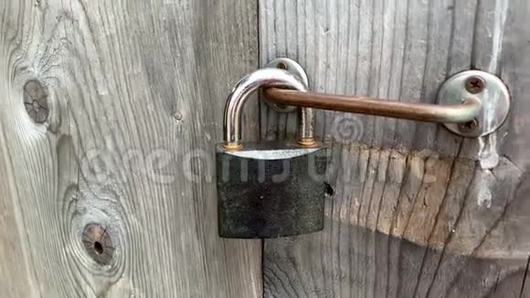 一只手触摸紧闭的木门上锁着的大金属挂锁私人财产保护概念视频的预览图