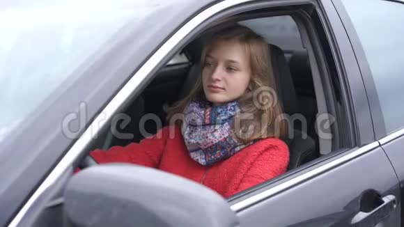 穿着红色保暖外套和五颜六色围巾的漂亮女人坐在车里视频的预览图