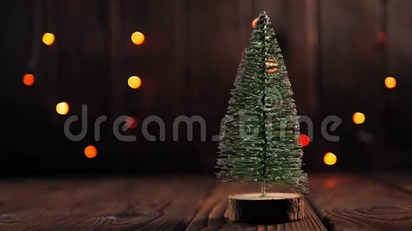 一棵木制背景上的小圣诞树上面有五颜六色的闪光视频的预览图