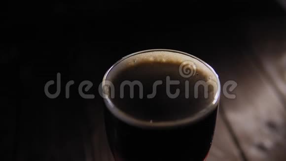 一整杯深色工艺啤酒在黑色背景上慢慢旋转特写镜头视频的预览图