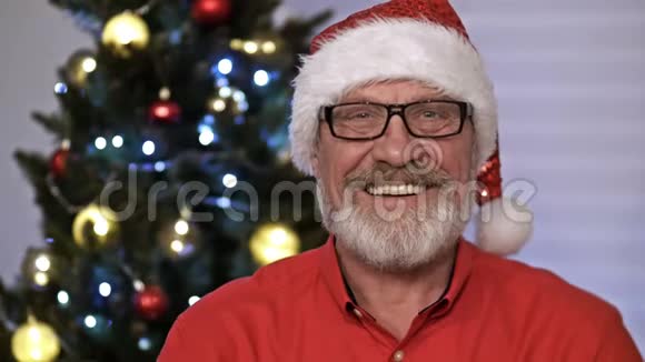 圣诞老人肖像坐在室内靠近装饰好的圣诞树有灯光圣诞快乐和节日快乐视频的预览图