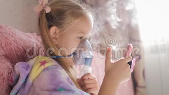 小女孩在家拿着吸入器面罩生病的孩子通过喷雾器呼吸婴儿使用治疗哮喘或视频的预览图