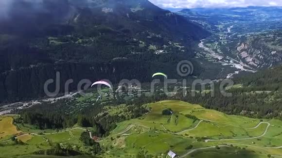 滑翔伞用降落伞在山上的青山和田野上飞行视频的预览图