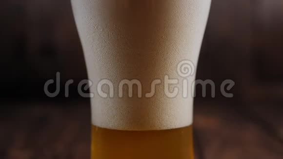 在木制背景上用泡沫和气泡装饰一杯轻啤酒视频的预览图
