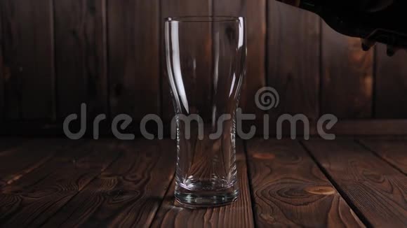 在木制背景下一杯浓墨重彩的啤酒慢慢地倒在杯子里视频的预览图