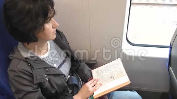 高加索女人坐在靠窗的火车上开着一本书视频的预览图