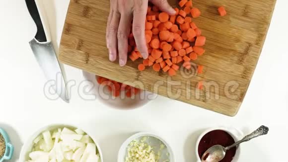 女人把切下来的胡萝卜放进碗里靠近白色背景视频的预览图