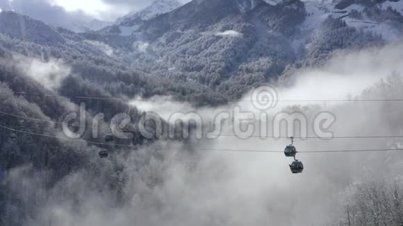 滑雪索道在雾蒙蒙的雾霭中穿行于雪山之间在阴天的时候用滑雪电梯运送人们到雪坡视频的预览图